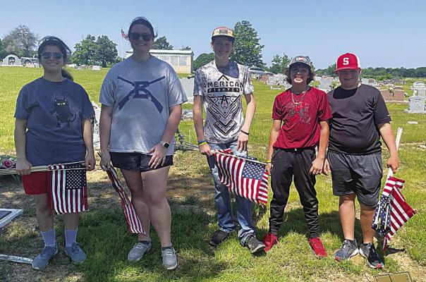 Soper 4-H Club members show their patriotism as they prepare to place American flags at veteran’s headstones for Memorial Day at the Soper Cemetery.